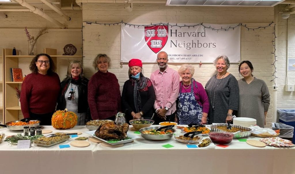 Havard Neighbors posing in front of Thanksgiving table of food